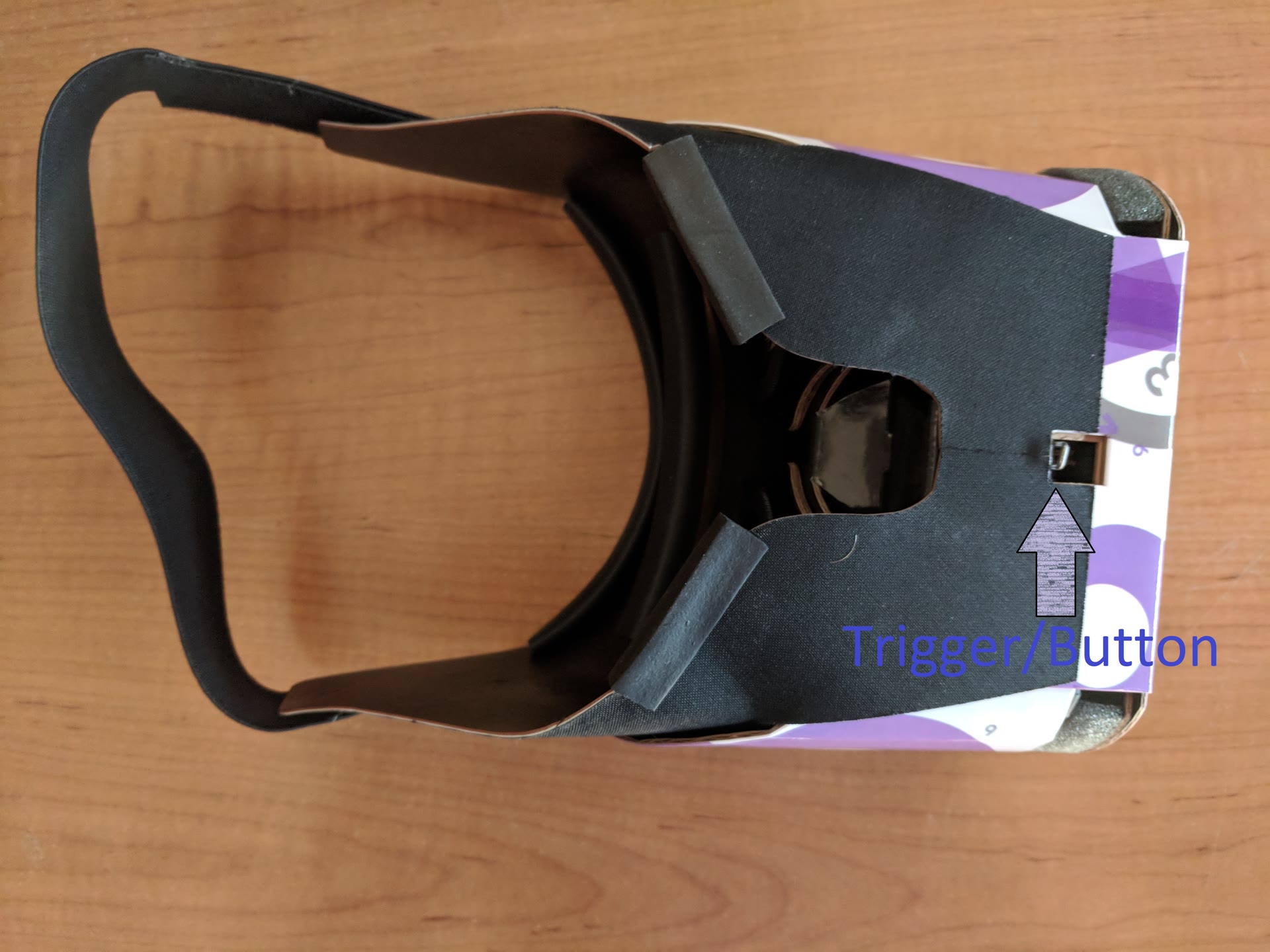 VR headset seen from below with the trigger button labeled